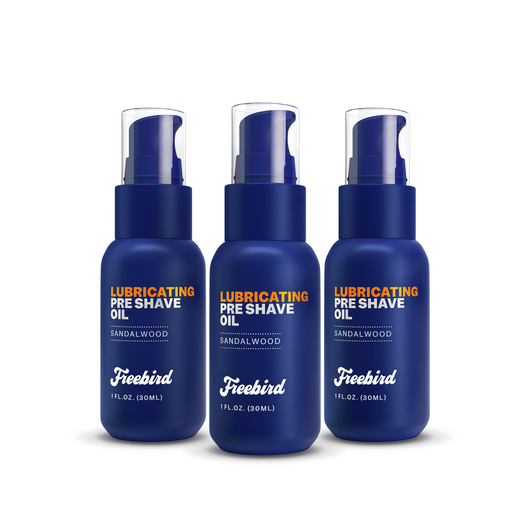 Three Freebird Lubricating Pre Shave Oil bottles, sandalwood scented with almond oil and pump dispensers, in blue packaging.
