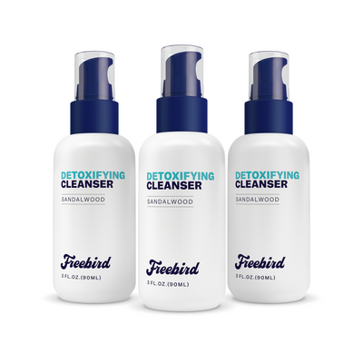 Three bottles of Freebird Detoxifying Bald Head Cleanser with blue pumps rest on a white background for an effective detox.